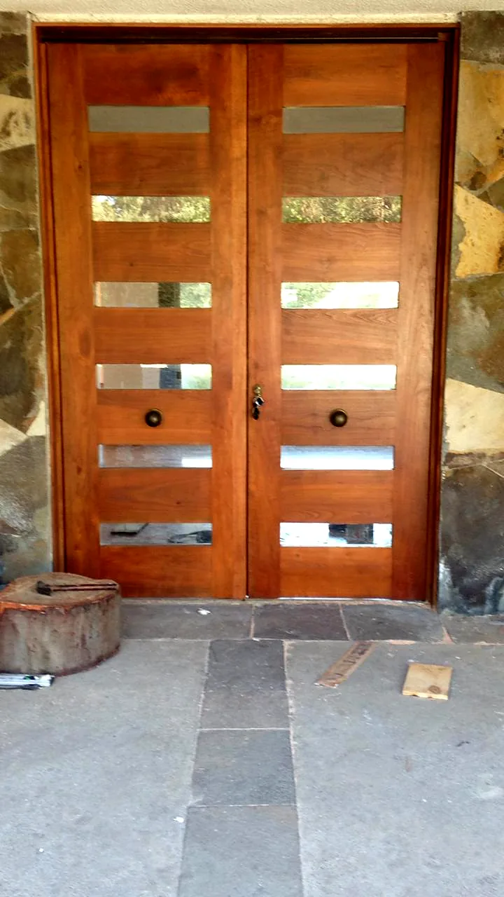 Puerta doble de madera con vidrios instalada en un muro de piedra