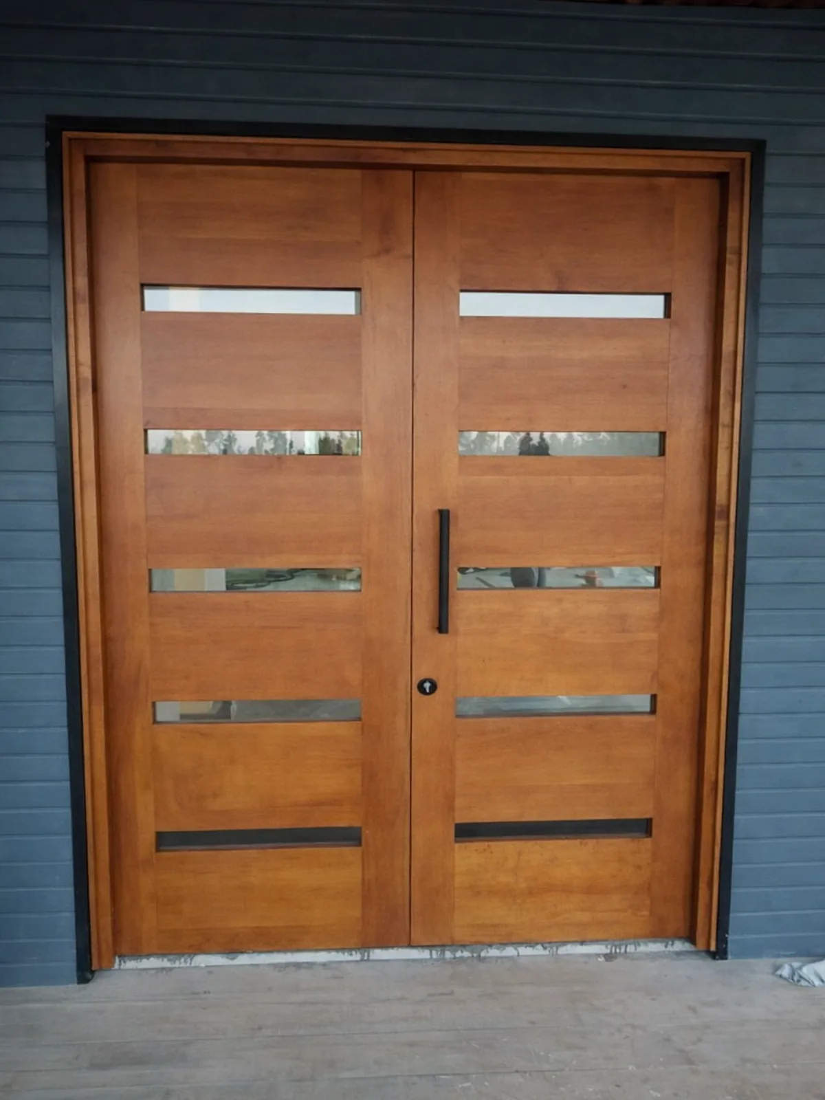 Puerta doble de madera con vidrios en fachada