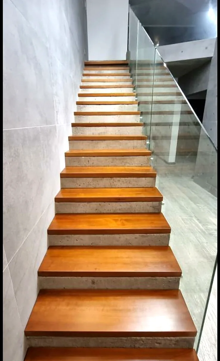 Escalera con peldaños de madera barnizada y baranda de vidrio